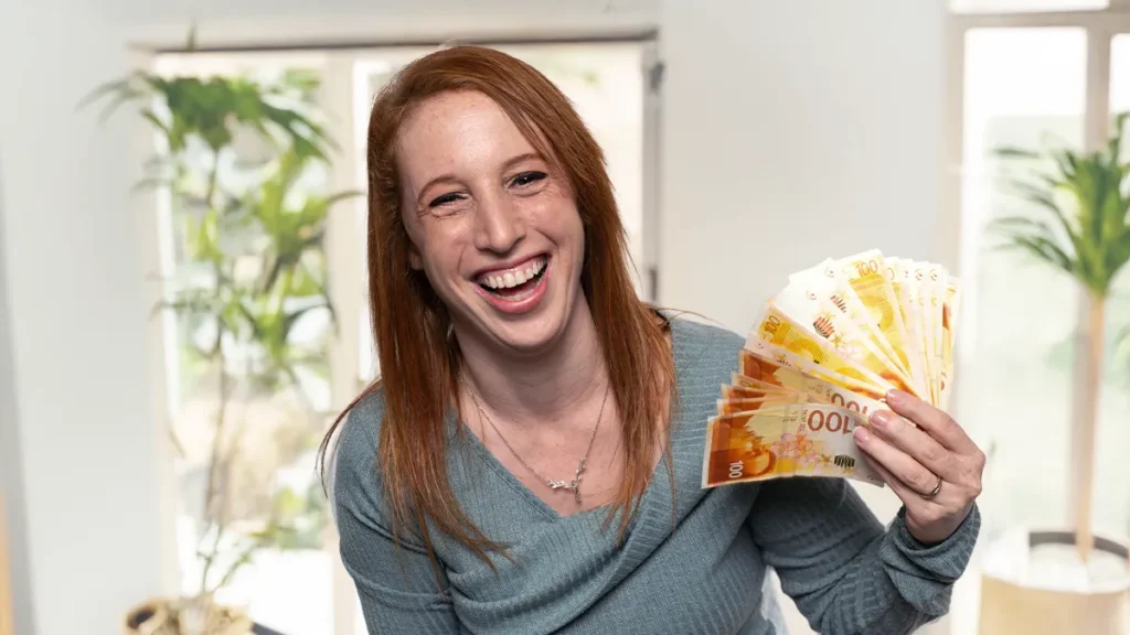 האופטימית מחזיקה שטרות ומחייכת